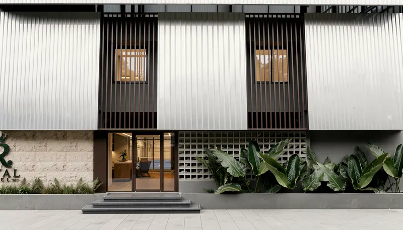 The entrance: dark louvres, a stone-clad base and a glazed door